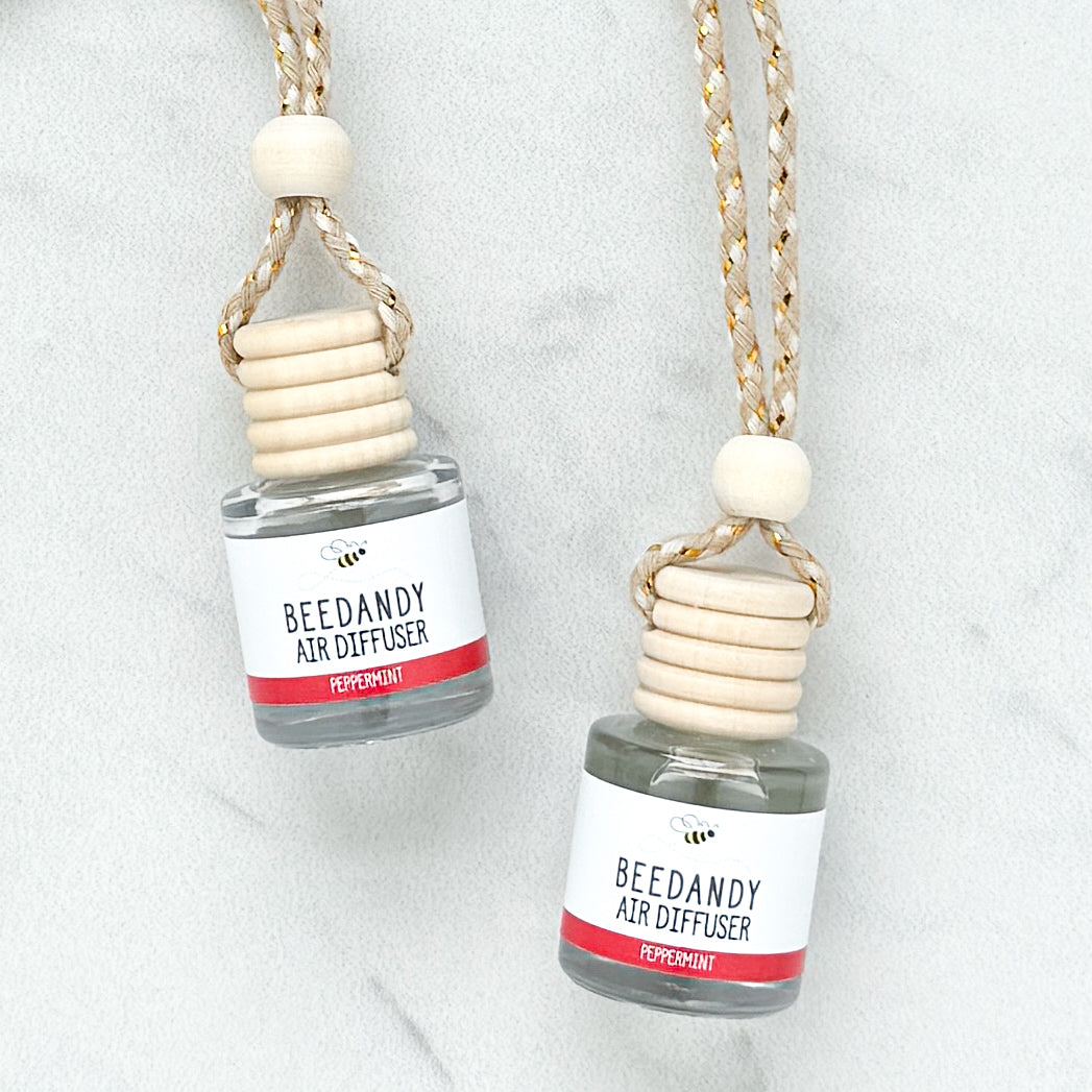 2 glass air diffusers with wooden lids, attached to braided ropes, labeled with white and red label "Peppermint"