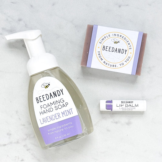 Beedandy lavender mint foaming hand soap bottle displayed with a bar soap and a lavender lip balm on a light background.