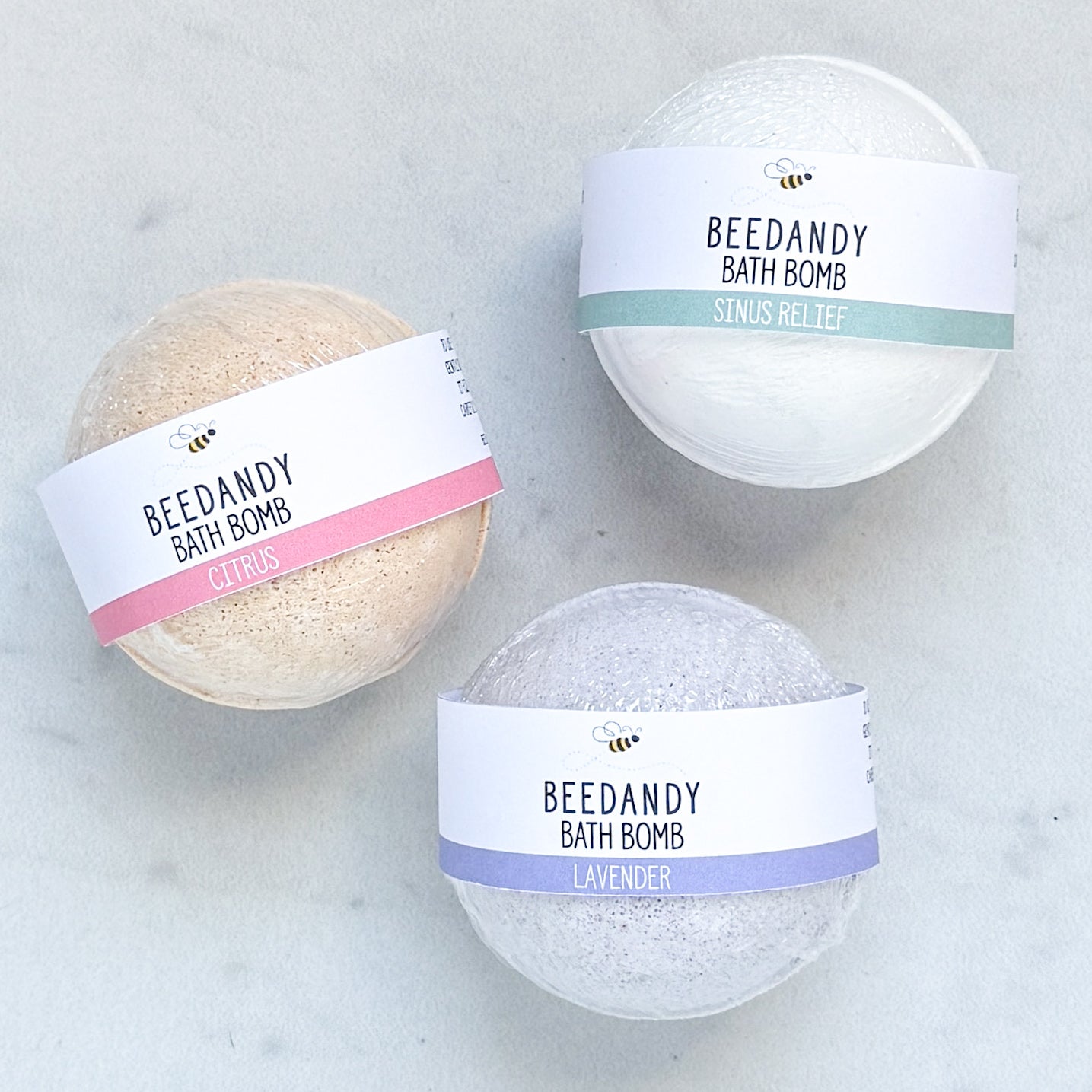 Three bath bombs with labels on a light gray background