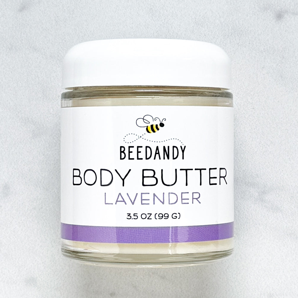 Beedandy Lavender Body Butter in a small clear glass jar with a white lid, shown on a light gray background. The label features a bee logo and reads “Body Butter, Lavender, 3.5 oz (99 g),” with a purple accent band at the bottom.