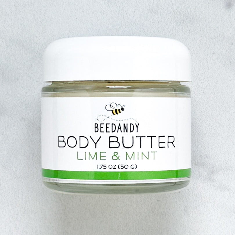 Beedandy Lime Mint Body Butter in a small clear glass jar with a white lid, shown on a light gray background. The label features a bee logo and reads “Body Butter, Lime Mint, 1.75 oz (50 g),” with a green accent band at the bottom.
