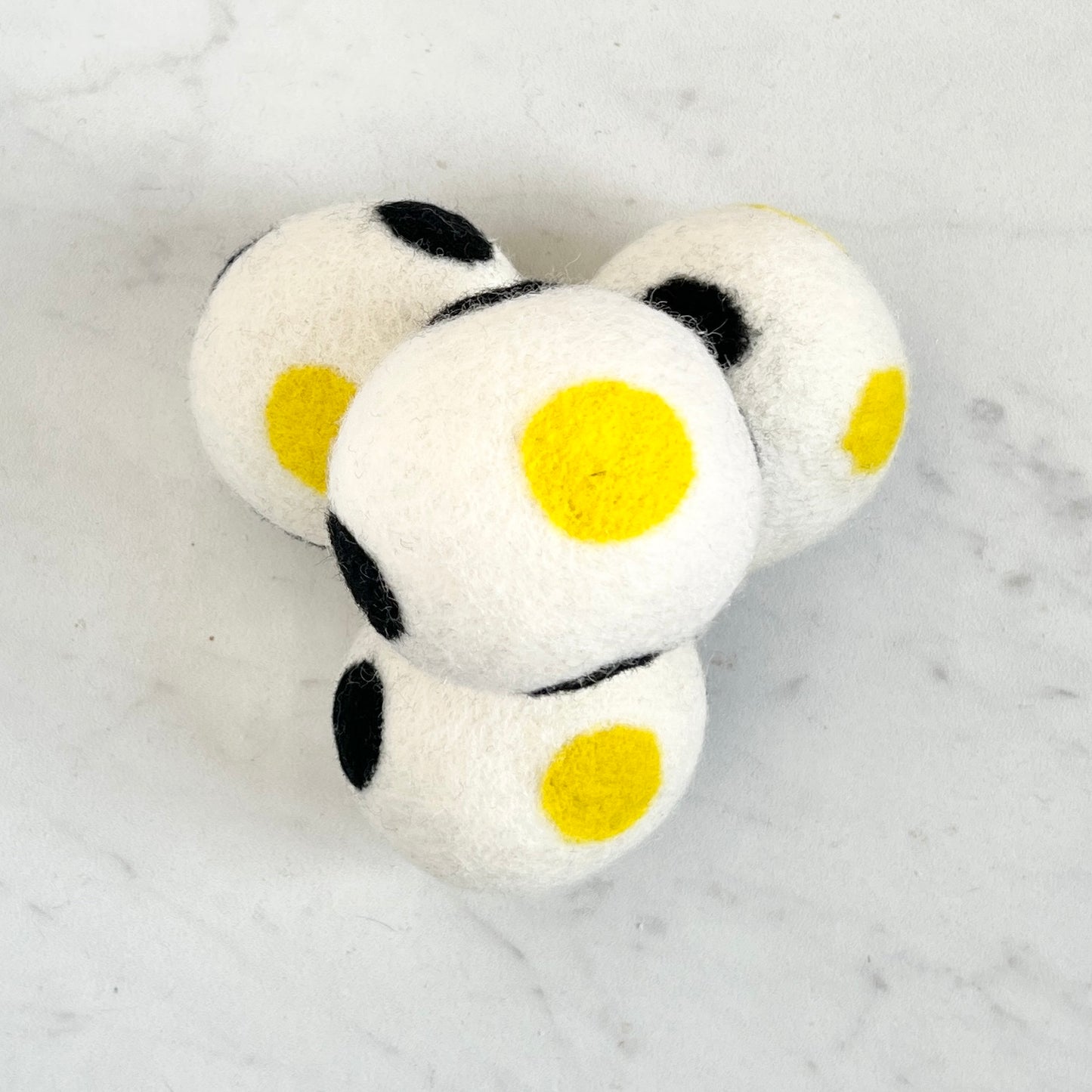 set of 4 white dryer balls with black and yellow dots, on white background