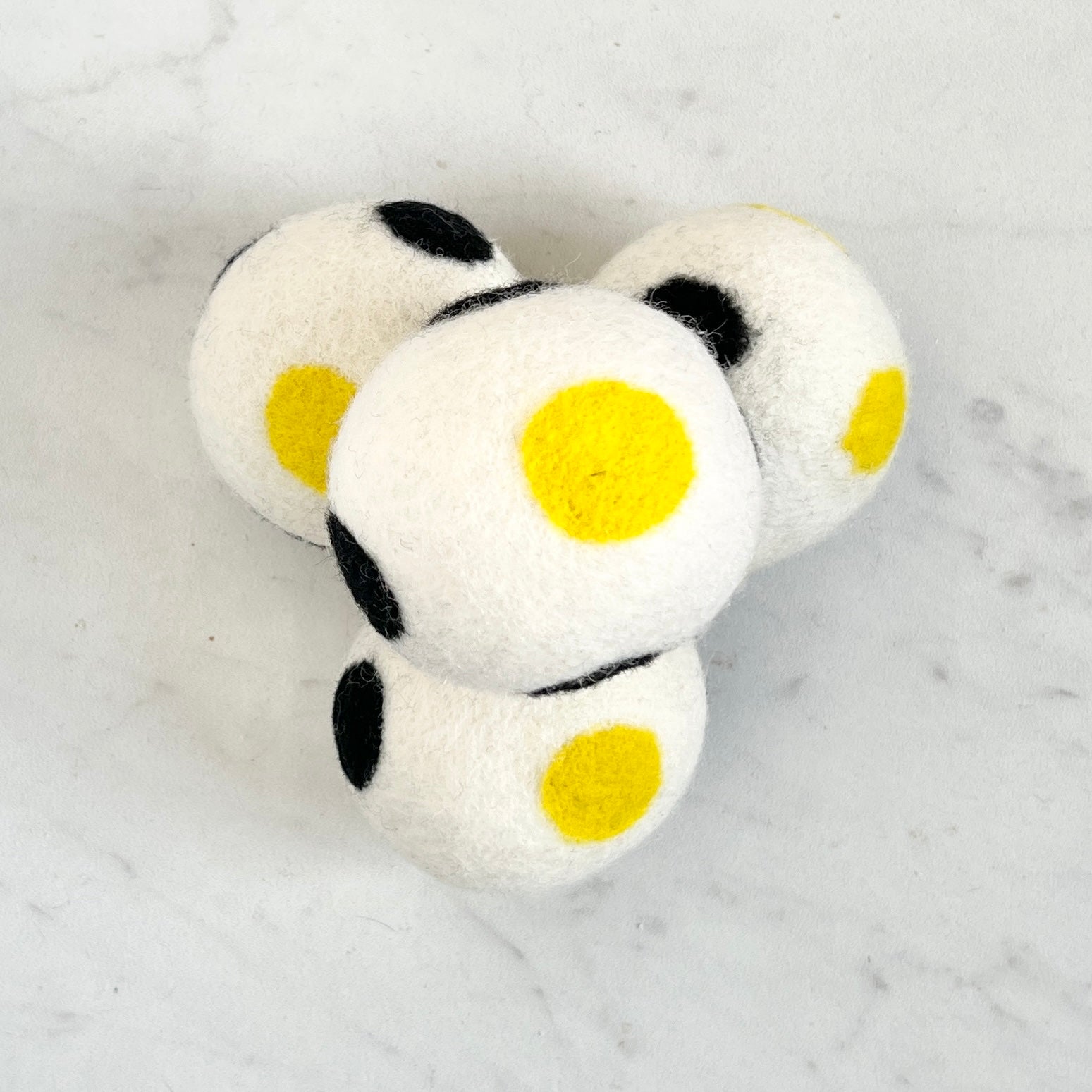 set of 4 white dryer balls with black and yellow dots, on white background