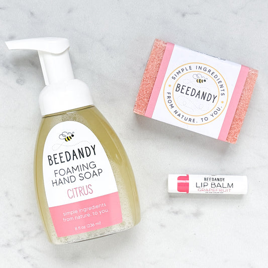 Beedandy citrus foaming hand soap bottle displayed with a bar soap and a grapefruit lip balm on a light background.