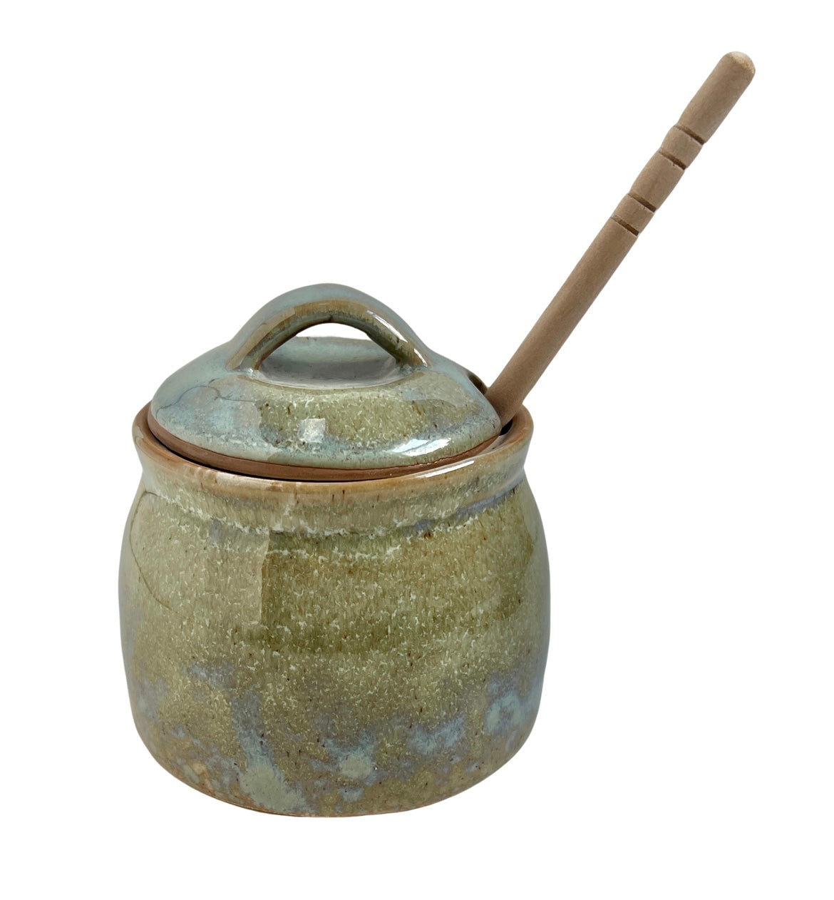 green honey pot with wooden dipper sticking out top against white background