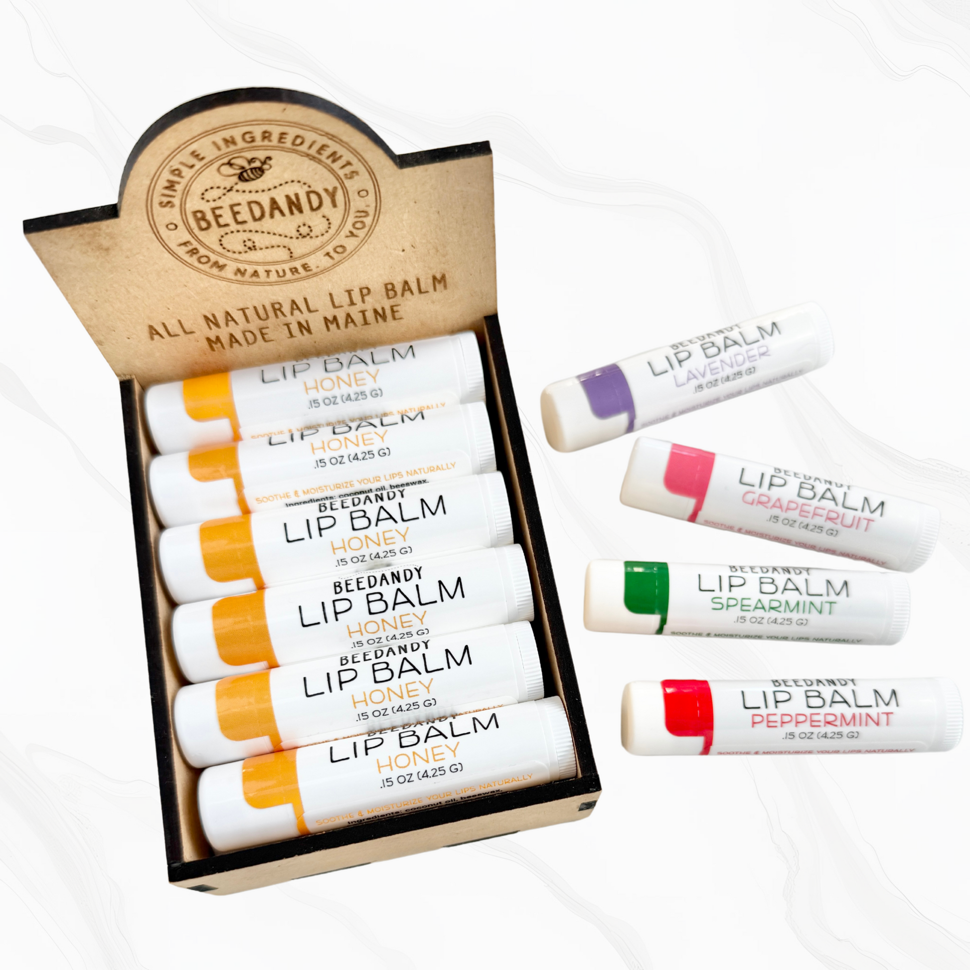 A wooden retail display box for lip balms, holding 12 stick-shaped balms, and has the brand name 'Beedandy' on it. Four lip balms are on white background beside it.