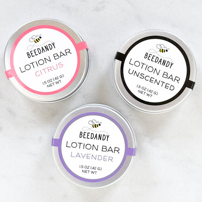 Three metal tins of BEEDANDY lotion bars with labels for citrus, unscented, and lavender on a white background.