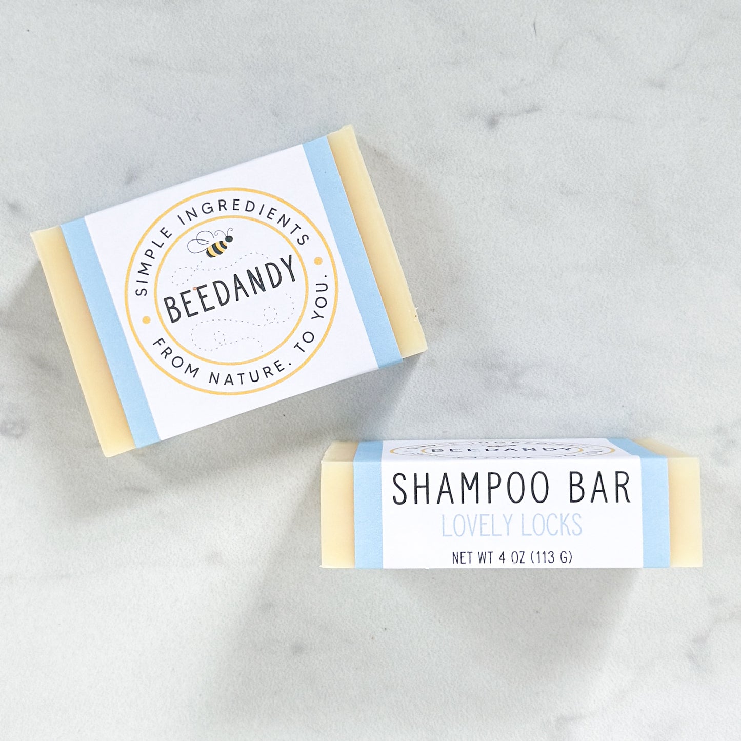 Two Beedandy shampoo bars with paper labels, shown on a light gray background.