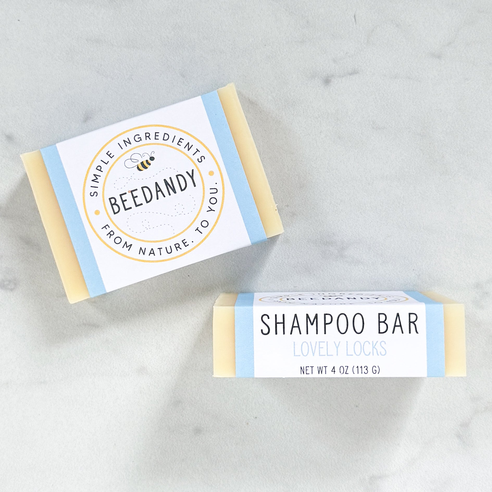 Two Beedandy shampoo bars with paper labels, shown on a light gray background.