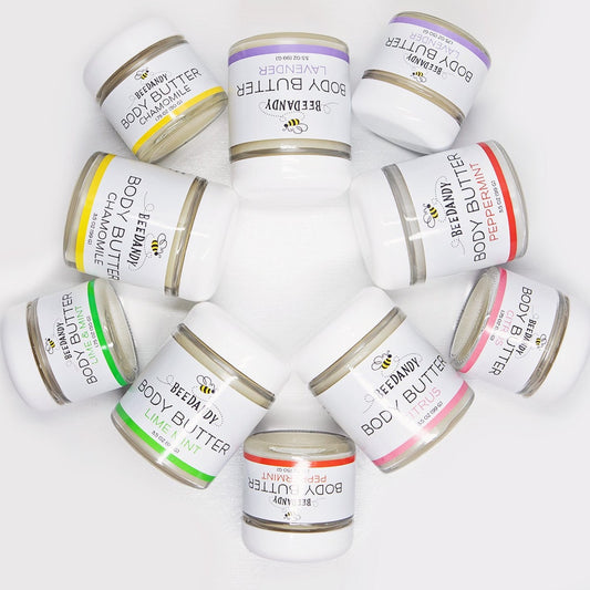 Multiple jars of body butter with various labels indicating different scents such as Lavender, Citrus, Peppermint, and Unscented, arranged in a circular pattern against a white background.