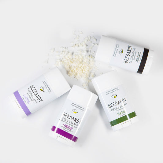 Flat lay of 4 Beedandy natural deodorant sticks in lavender, tea tree, and unscented varieties on a white background.