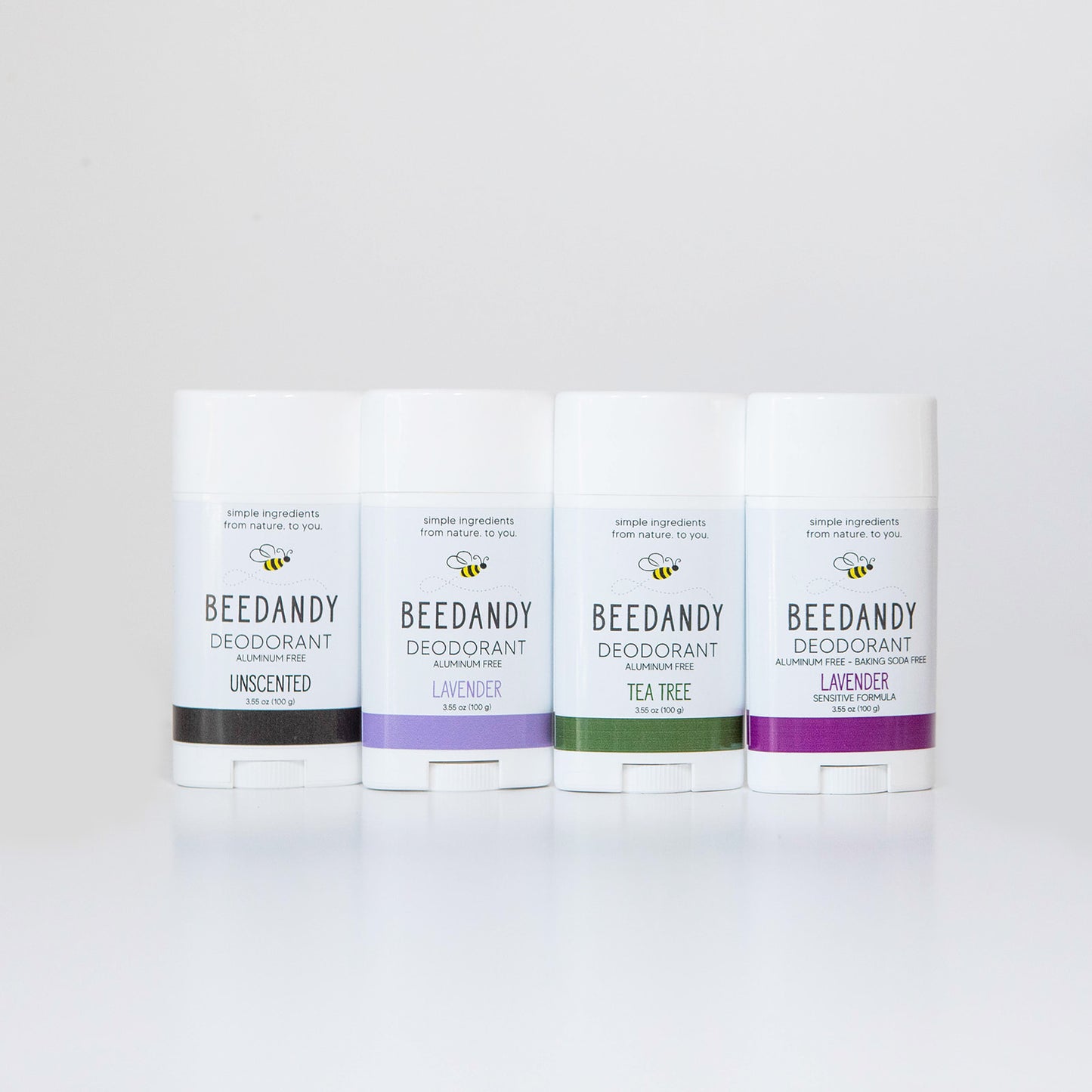4 Beedandy natural deodorant sticks in lavender, tea tree, and unscented varieties standing up on a white background.