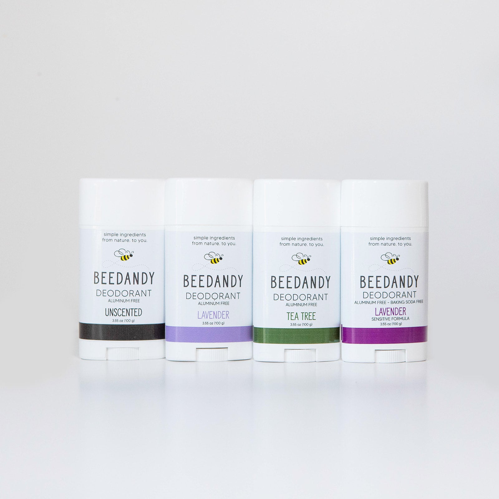 4 Beedandy natural deodorant sticks in lavender, tea tree, and unscented varieties standing up on a white background.