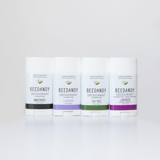 4 Beedandy natural deodorant sticks in lavender, tea tree, and unscented varieties standing up on a white background.